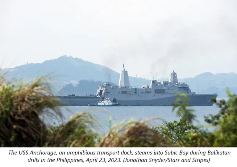 A large ship in the water near some trees.