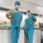 Two doctors standing in a room with their hands on their hips.