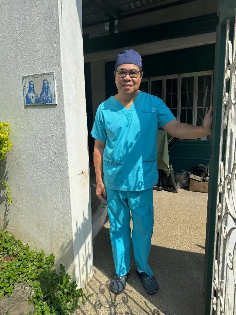 A man in blue scrubs standing outside of a building.