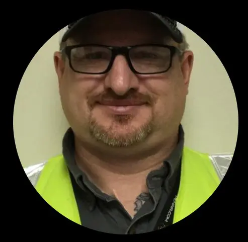 A man wearing glasses and a safety vest.