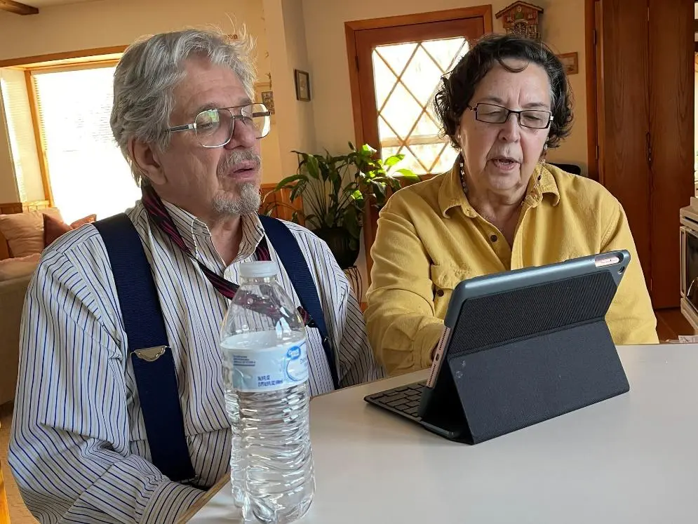 A man and woman sitting at a table with a tablet.