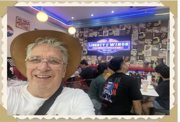 Man with hat smiling in restaurant.