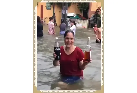 Woman in flood holding drinks, smiling.