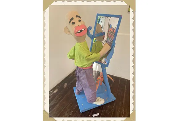 Puppet character painting in a mirror.