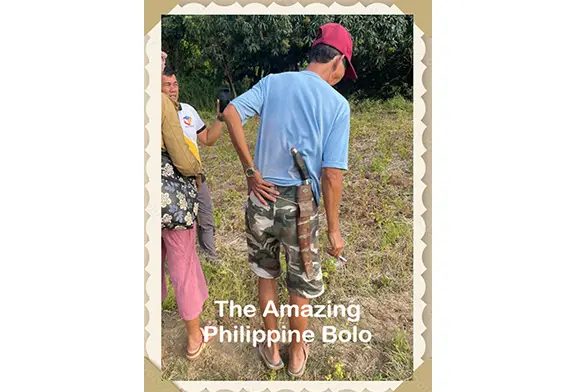 Man holding a bolo knife in nature.