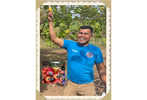 Man smiling while holding fruit outdoors.