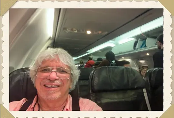 Smiling passenger taking a selfie on airplane.