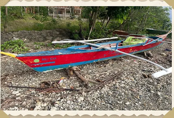 Colorful wooden boat on pebbled shore.