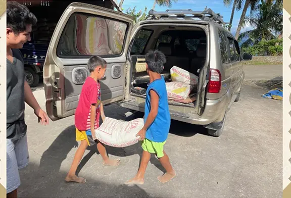 Children loading bags into a vehicle.