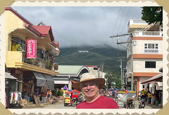 Man smiling in a bustling street scene.