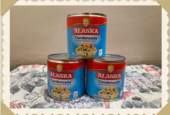 Three cans of Alaska condensed milk.