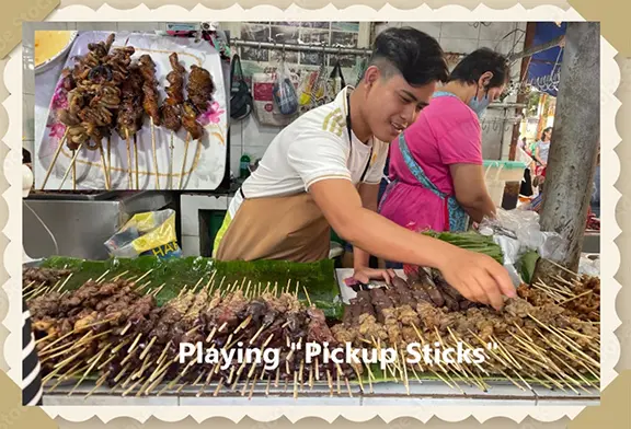 Young man selecting skewers at market.