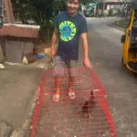 Man holding a red cage with chicken.