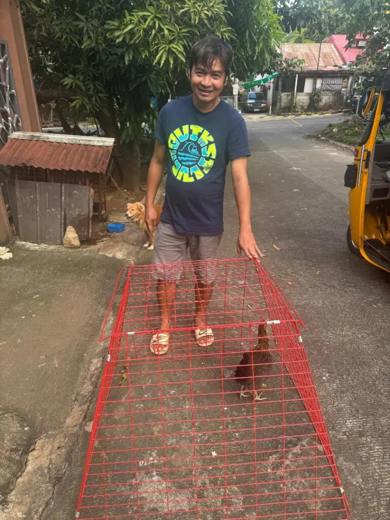 Man holding a red cage with chicken.