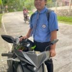 A man standing next to a motorcycle on the street.