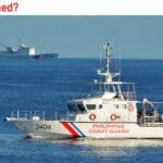 A coast guard boat in the ocean with two other boats.