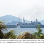 A large ship in the water near some trees.