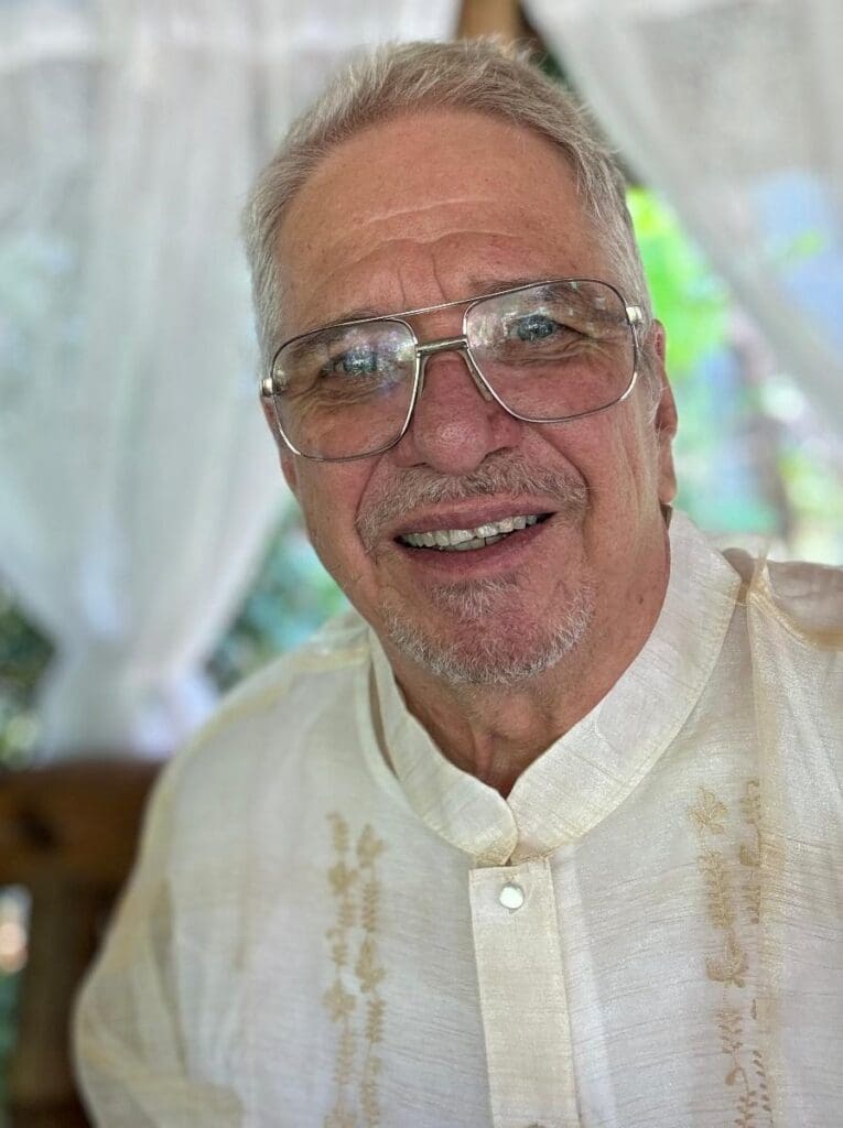 A man with glasses and white shirt smiling.