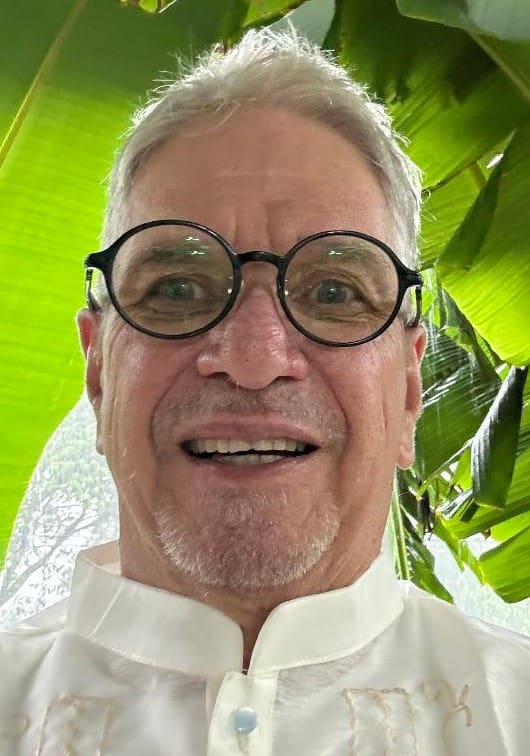 A man with glasses and white shirt smiling for the camera.