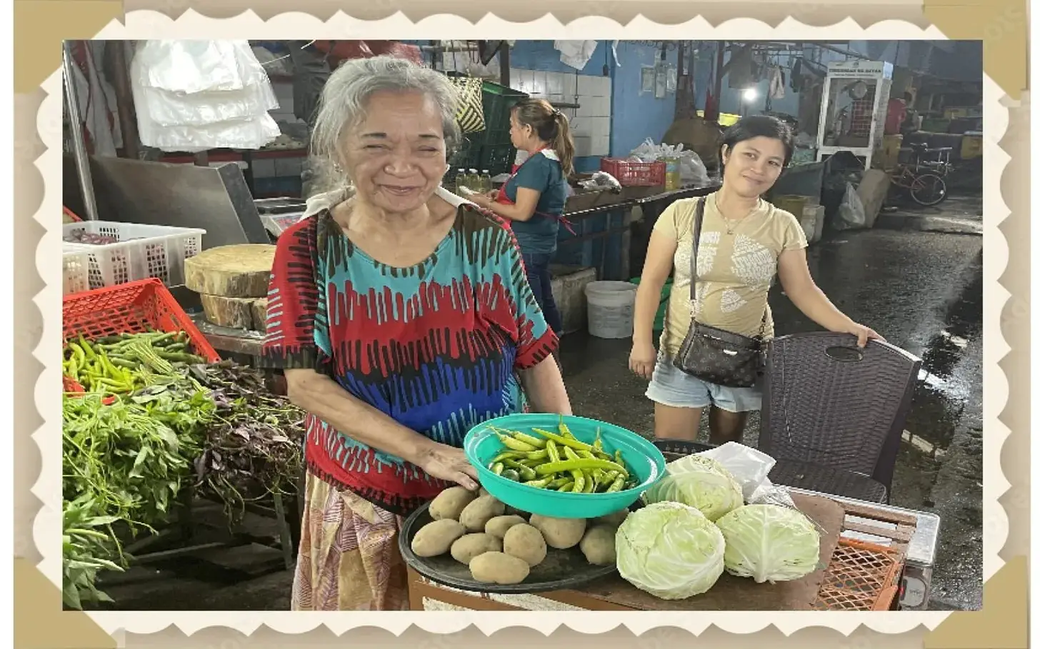 A woman holding a bowl of vegetables at an outdoor market.